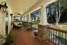 the porch is covered with wood and has an iron railing, potted plants, and hanging lanterns