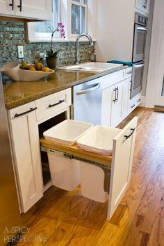 a kitchen with wooden floors and white cabinets has an open dishwasher in the middle