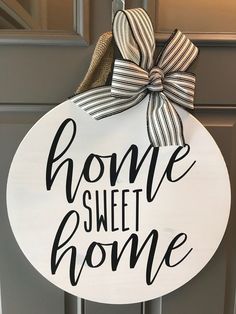 a sign that says home sweet home hanging on the front door with a bow around it