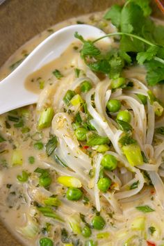 thai coconut noodle soup in a bowl with a spoon and garnishes