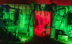 an outdoor area with green and red lights on the walls, decorated with fake skeletons