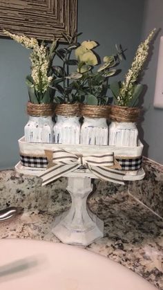 mason jars with flowers in them are sitting on a bathroom counter