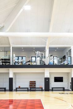 an indoor gym with hard wood flooring and white walls, large windows on the second floor