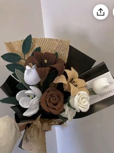 a bouquet of crocheted flowers is displayed on a table with white and brown decorations