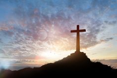 a cross on top of a hill at sunset