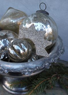 silver ornaments in a metal bowl on a table