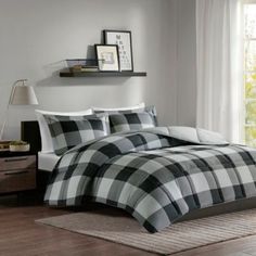 a bed with plaid comforter and pillows on top of it in a room next to a window