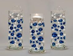 three glass candles with blue and white balls in the bottom one candle is lit up