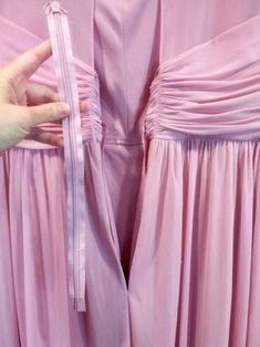 two bridesmaids in pink dresses with one holding the other's hand over their waist