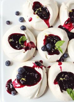 small pastries with blueberry sauce and mint leaves on a white plate, ready to be eaten