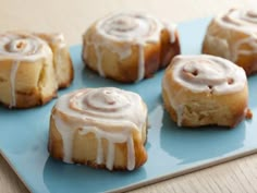 several cinnamon rolls on a blue plate with icing drizzled over them