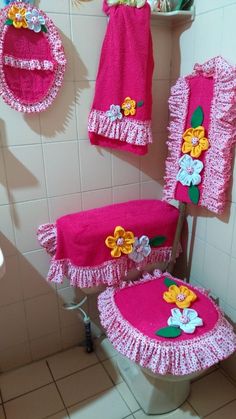 a bathroom with pink towels and flowers on the back of the toilet, along with other accessories