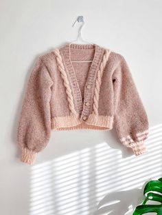 a pink sweater hanging on a white wall