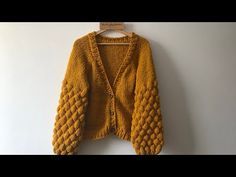 a yellow cardigan sweater hanging on a white wall