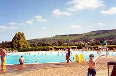 many people are in the water at a large swimming pool with mountains in the background