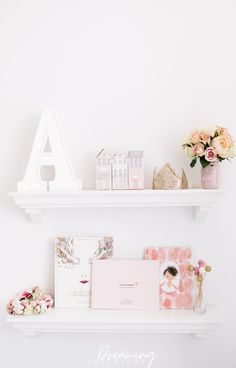 two white shelves with flowers and greeting cards on them, one shelf has a letter