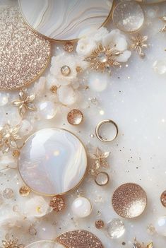 an assortment of gold and white jewelry on top of a marble surface with flowers in the background