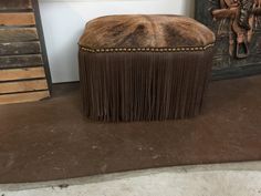 a brown ottoman sitting on top of a floor next to a fireplace