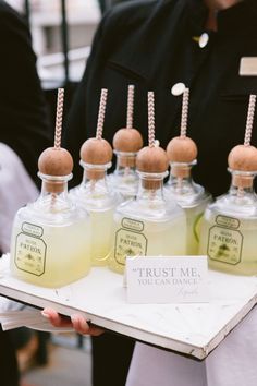 a person holding a tray with some bottles and straws on it that are labeled trust me, you can dance