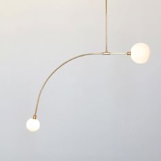 three white balls hanging from a brass colored light fixture in a room with gray walls