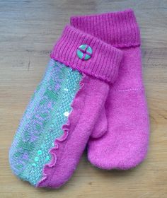 two pink mittens sitting on top of a wooden table