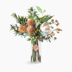 a vase filled with lots of flowers and greenery on top of a white surface