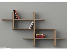 three wooden shelves with books on them against a gray wall in an office or living room