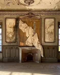 an old room with peeling paint on the walls and paintings hanging from the ceiling above it