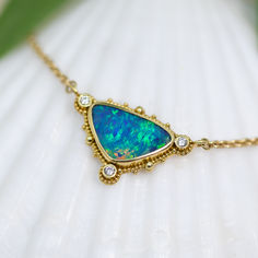 Capture the beauty of the tropical ocean and place it around your neck with this 18K Treasure Gold granulated pendant. This one-of-a-kind handcrafted necklace features a stunning 3.4ct blue/green Australian opal doublet and 3- 2mm VS/G-H round diamonds set in solid 18K gold made with 400 year-old sunken treasure recovered from the Caribbean. This is then suspended on an elegant 18K gold chain. Dimensions: 7/8” x 5/8” (24mm x 16mm) including bail. Necklace length overall: 18" Treasure Gold, Sunken Treasure, Sea Opal, Tropical Ocean, Round Diamond Setting, 18k Gold Chain, Cake Stuff, Products Photography, Jewelry Lookbook