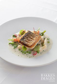 a white plate topped with fish and vegetables