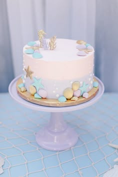 there is a white cake with blue and gold decorations on the top, sitting on a table