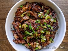 a bowl filled with meat and vegetables on top of a wooden table