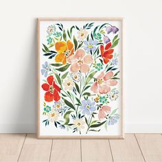 an art print with watercolor flowers on white paper in front of a wooden floor