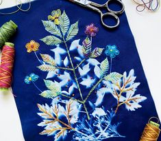 a blue bag with flowers on it next to some thread and spools of thread