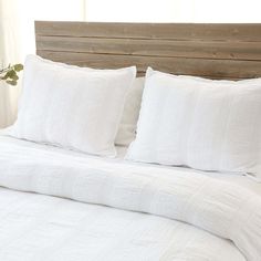 a bed with white linens and pillows on it