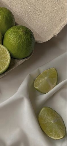 limes are sitting on a white table cloth