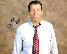 a man wearing a white shirt and red tie with blue writing on the wall behind him