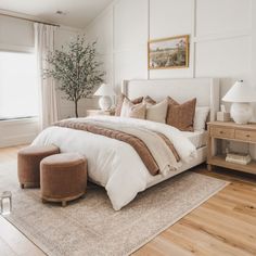 a bedroom with white walls and wood flooring has a large bed in the center