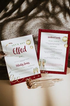 two red and white wedding cards sitting on top of a table next to each other