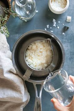 someone is pouring water into a pan with rice in it and other dishes on the table