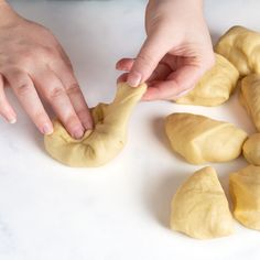 someone is kneading dough into small pieces on a white counter with their hands