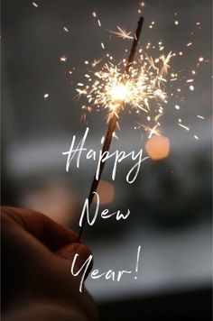 someone holding a sparkler with the words happy new year written on it in white