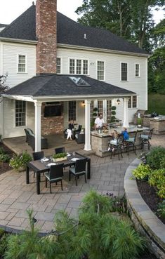 an outdoor dining area with chairs, tables and a brick patio in front of a large white house