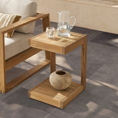 a wooden table with a vase on it next to a couch and coffee mugs