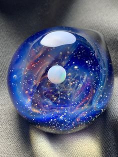 a blue and white glass object sitting on top of a gray surface with bubbles in it