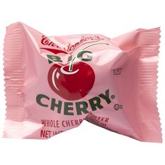 a bag of cherry candy sitting on top of a white table next to an apple