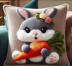 a crocheted bunny holding a carrot on top of a pillow in a living room