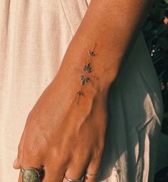 a woman's hand with a flower tattoo on her left wrist and two rings