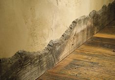 the corner of a room with wood flooring and peeling paint on it's walls