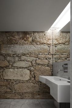 a bathroom with a sink and stone wall